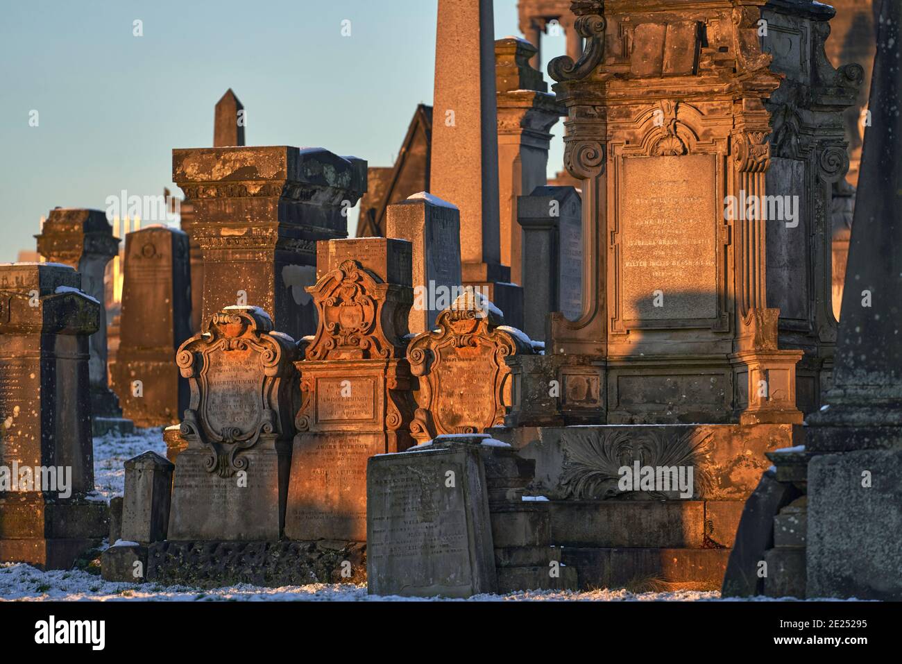 Gros plan d'un groupe de pierres angulaires et de monuments qui se sont emparés lors d'une journée hivernale enneigée dans la nécropole de Glasgow. Banque D'Images