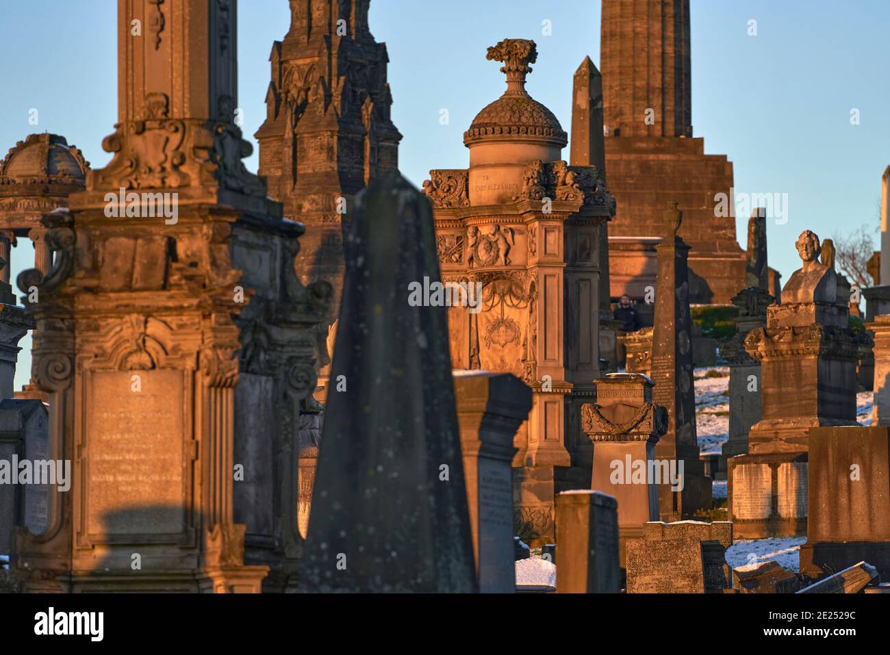 Gros plan d'un groupe de pierres angulaires et de monuments qui se sont emparés lors d'une journée hivernale enneigée dans la nécropole de Glasgow. Banque D'Images