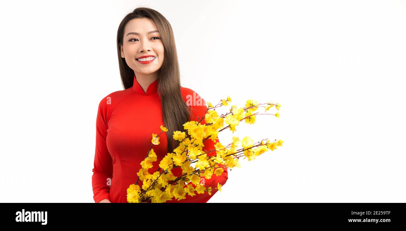 Femme asiatique avec robe traditionnelle vietnamienne ao dai tenant fleur de fleur pour les décorations. Nouveau concept d'année lunaire Banque D'Images
