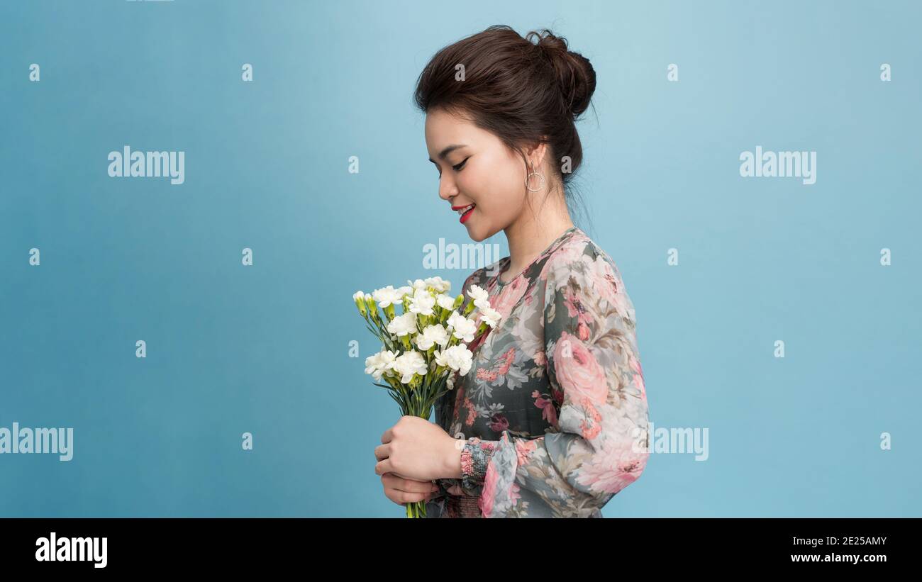 Portrait de la femme à l'aspect agréable a un maquillage minimal, large sourire, reçoit des fleurs en occasion spéciale, isolé sur fond bleu clair Banque D'Images