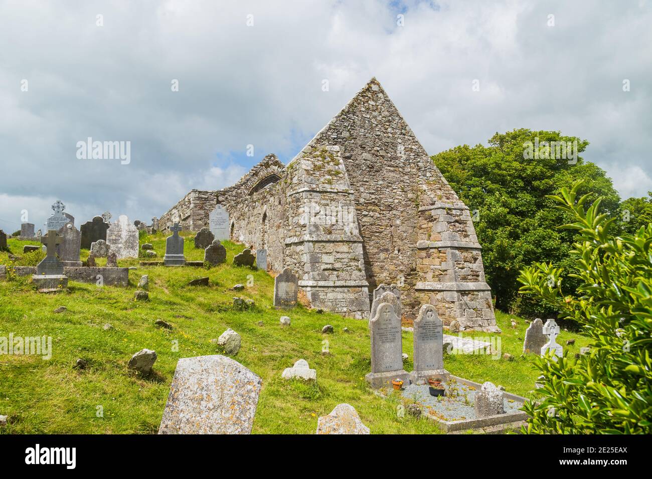 Tour en pierre et quelques ruines d'une colonie monastique construite à l'origine au 6ème siècle dans la vallée de Glendalough, comté de Wicklow, Irlande. Banque D'Images