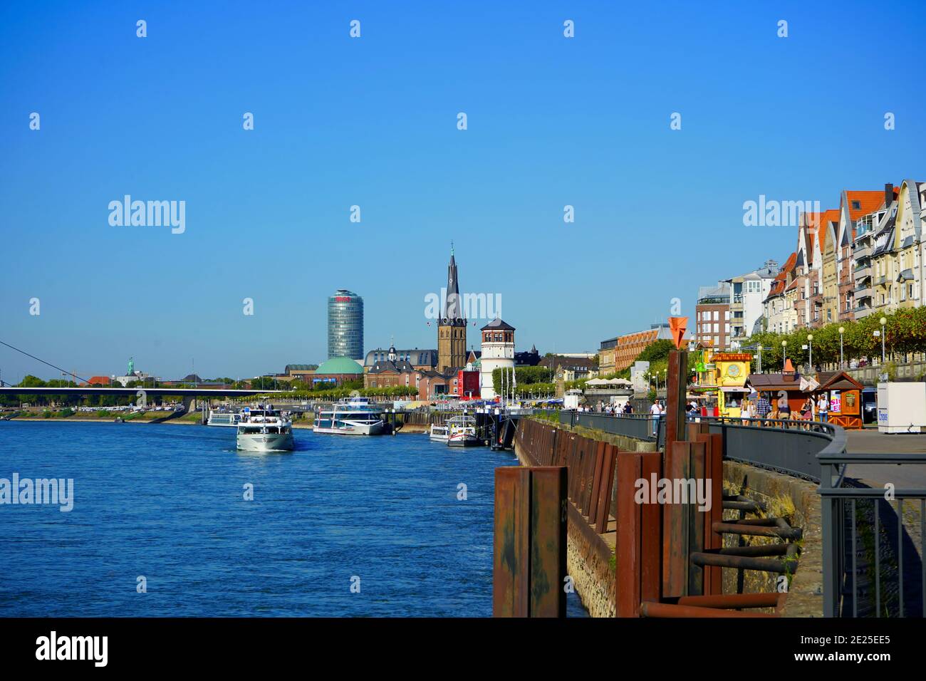 Rive du Rhin par une journée ensoleillée avec ciel bleu. Tour du château et église de Lambertus en arrière-plan. Banque D'Images