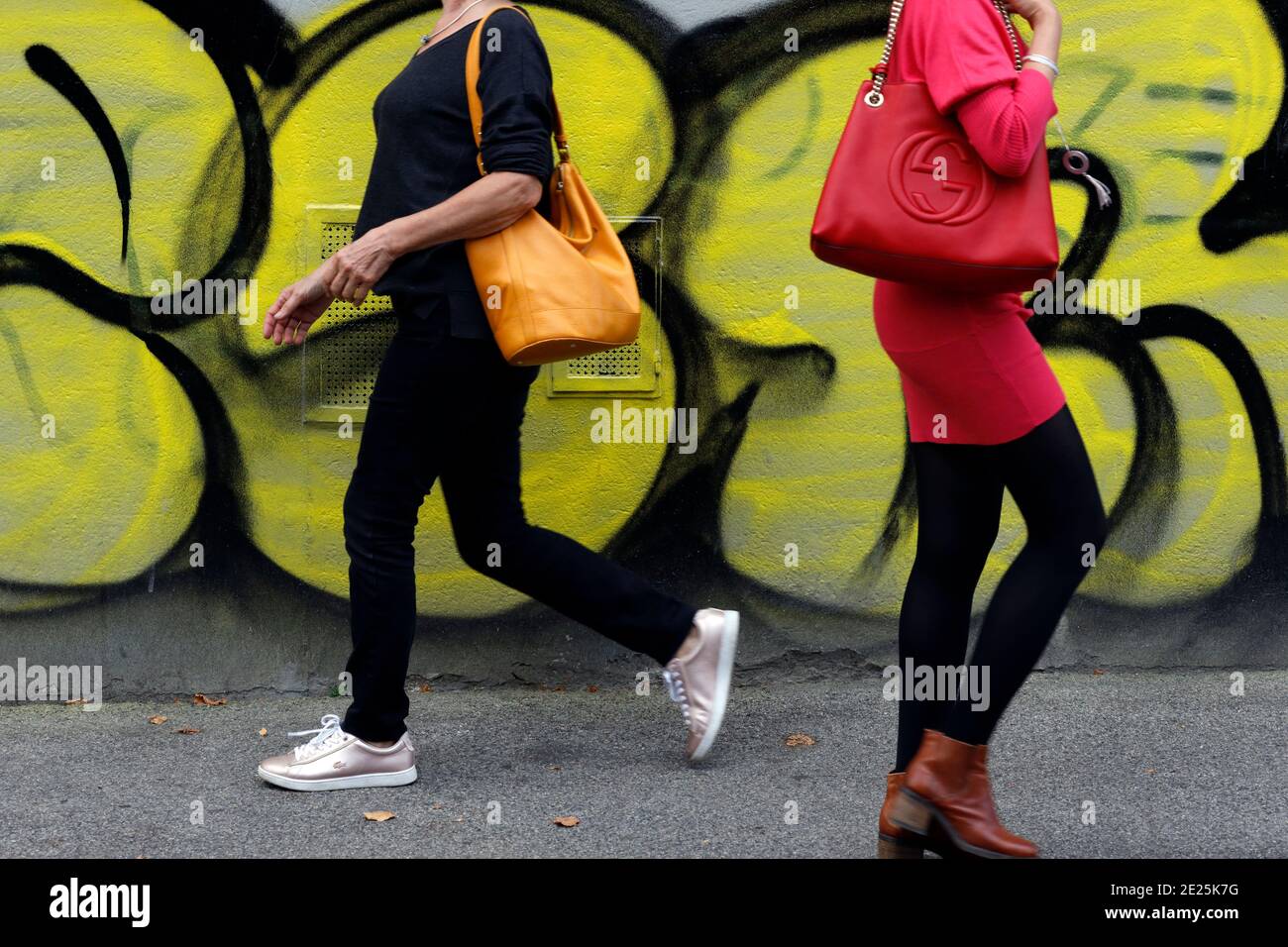 Femmes marchant devant un mur couvert de graffiti coloré. Banque D'Images