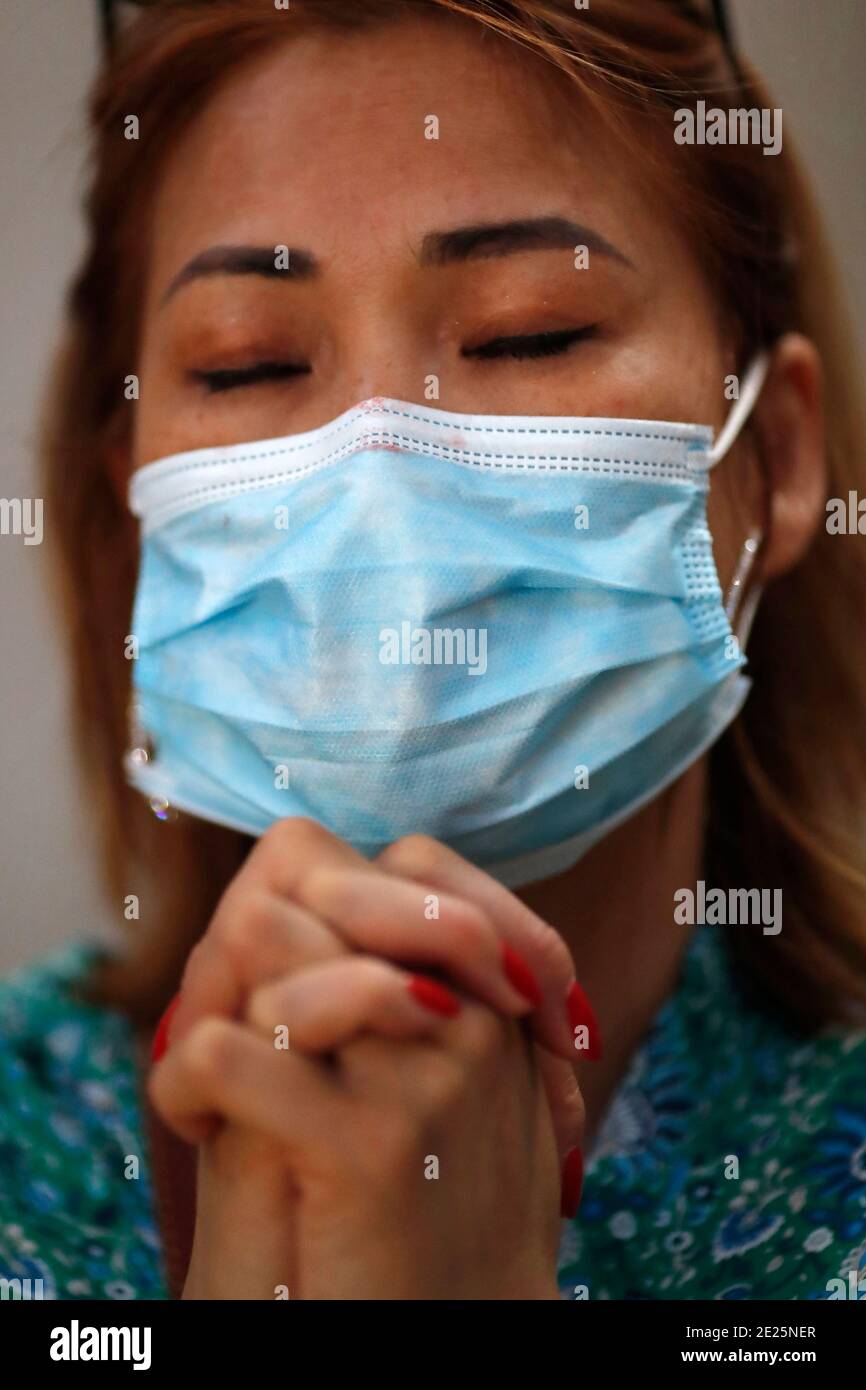 Femme avec masque chirurgical priant dans l'église pendant l'épidémie de coronavirus. Covid-19. Banque D'Images