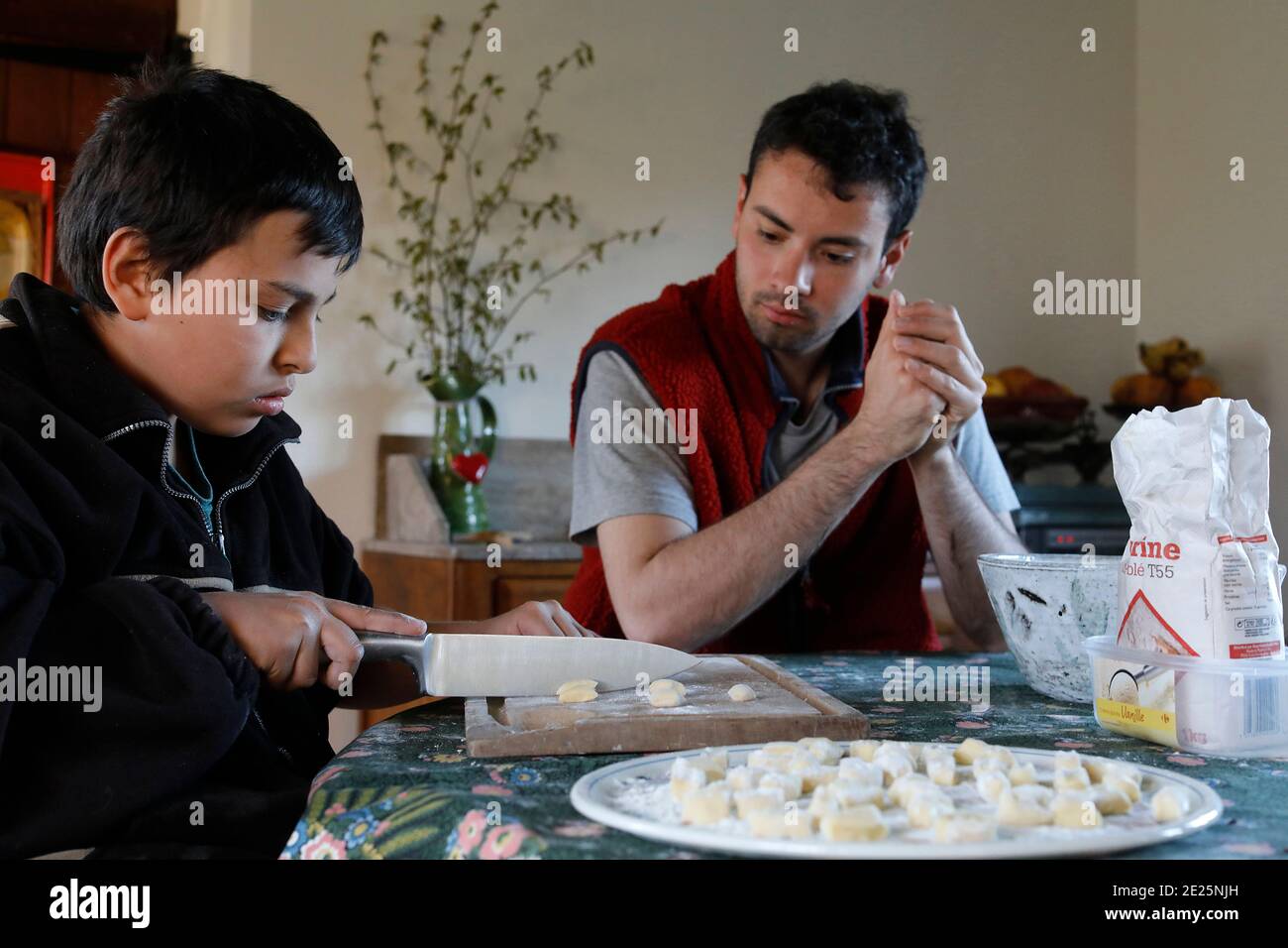 Jeune homme montrant à son frère cadet comment faire des gnocchi. Eure, France. Banque D'Images