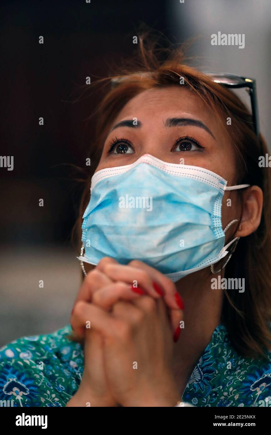 Femme avec masque chirurgical priant dans l'église pendant l'épidémie de coronavirus. Covid-19. Banque D'Images