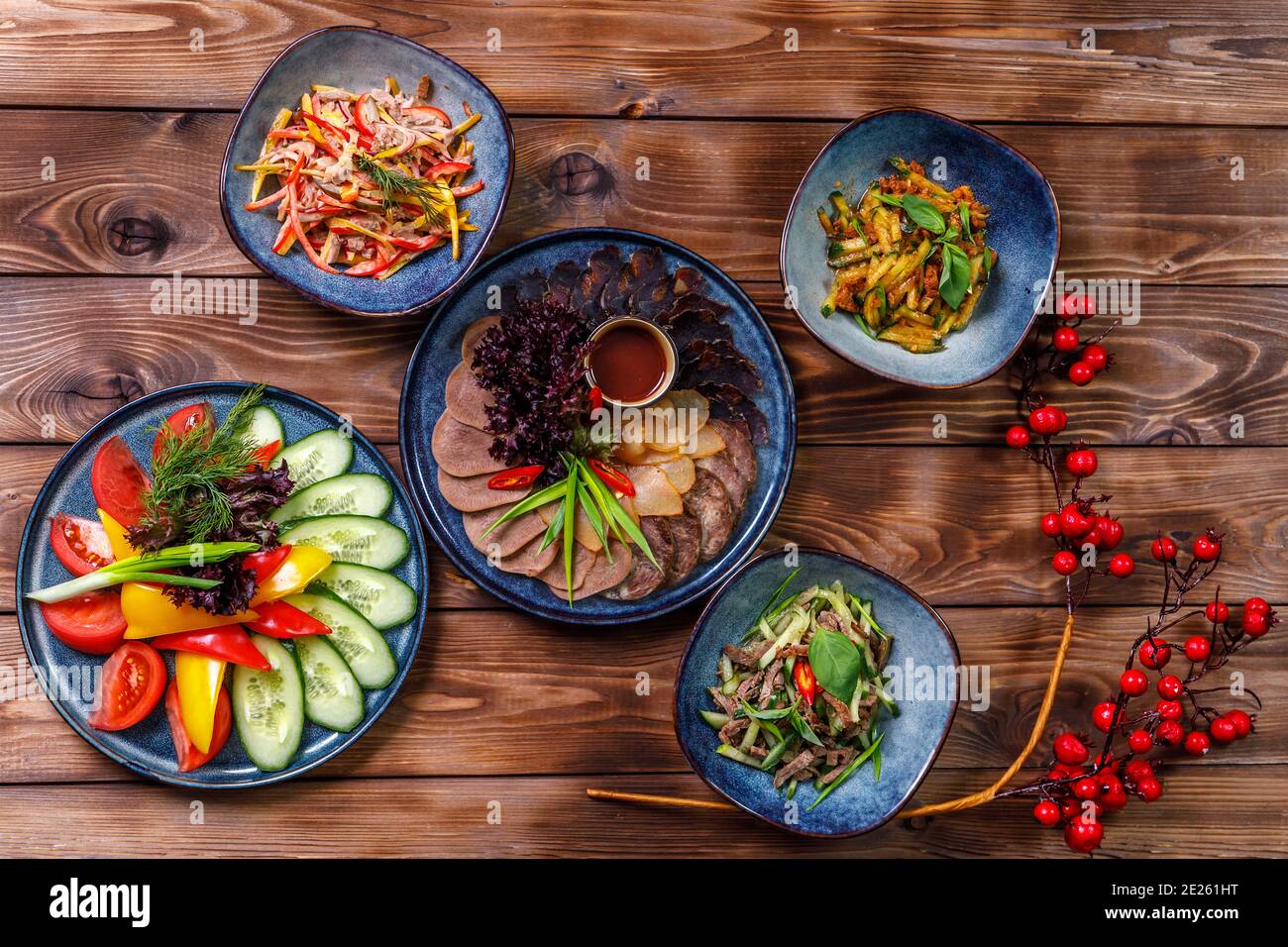 Agencement plat de divers plats avec des tranches de légumes, des viandes coupées, des salades sur fond de bois brun. Banque D'Images