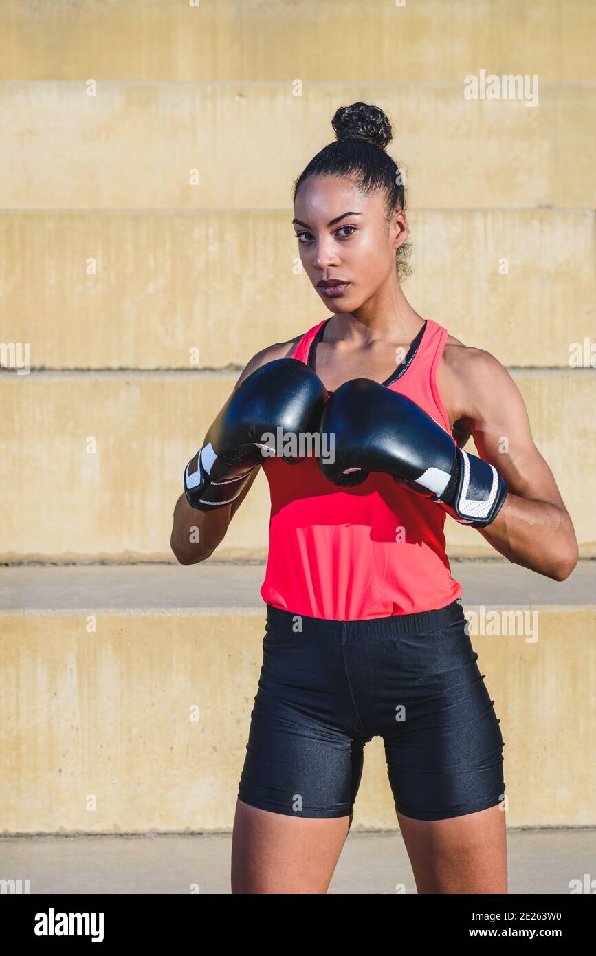 portrait vertical d'une athlète afro-américaine vêtue de noir gants de boxe et debout en position de défense Banque D'Images