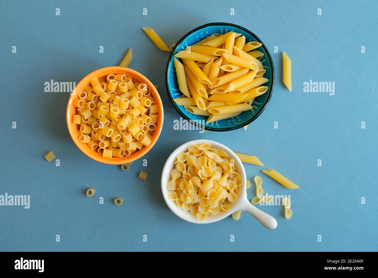 pâtes de type penne, farfalle tonde papillon et dalitini sur fond bleu clair. pâtes dans un bol en céramique. bol bleu orange blanc. abstrait, pâtes. t Banque D'Images