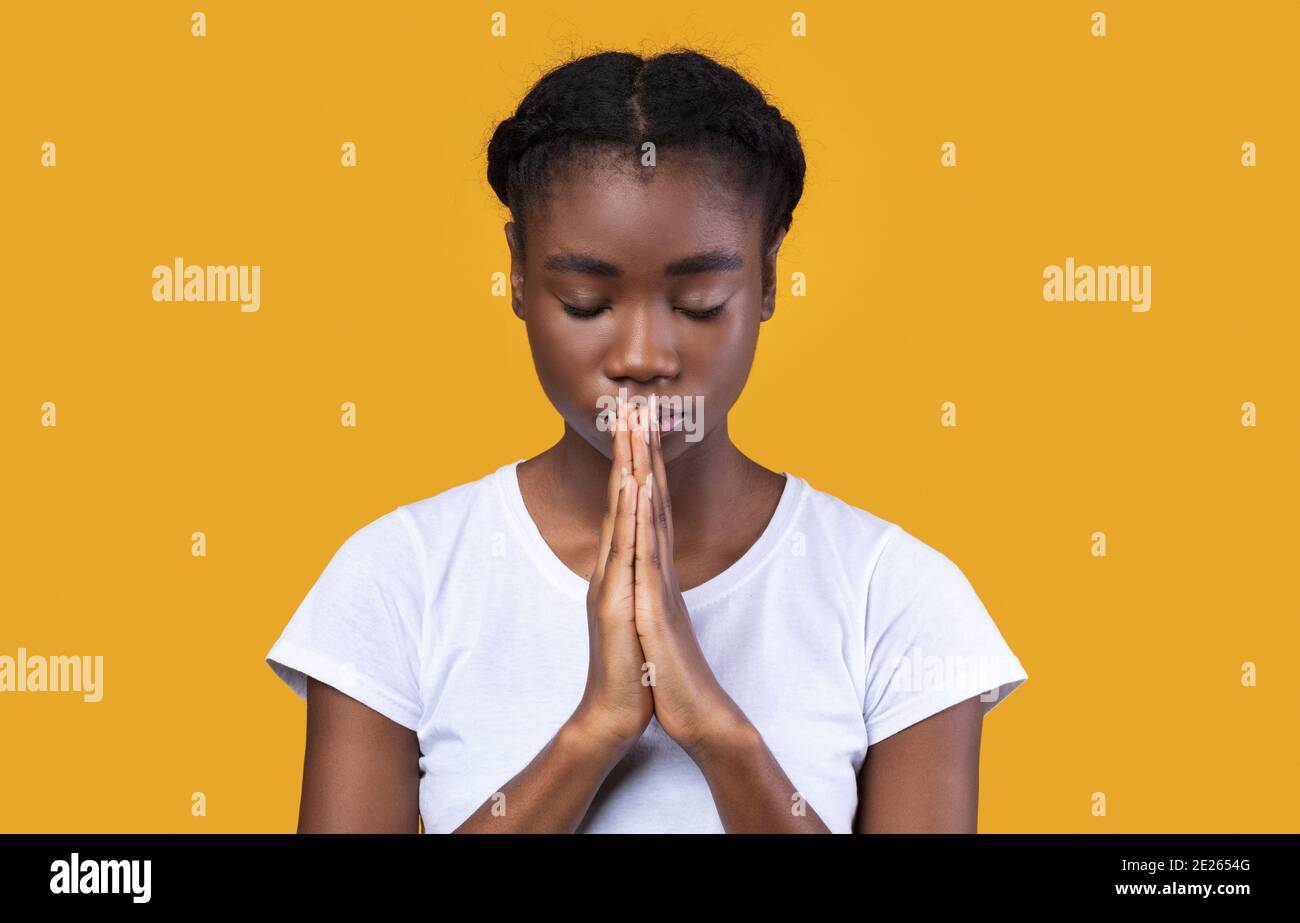 Paisible African Lady priant debout avec les yeux fermés dans Studio Banque D'Images