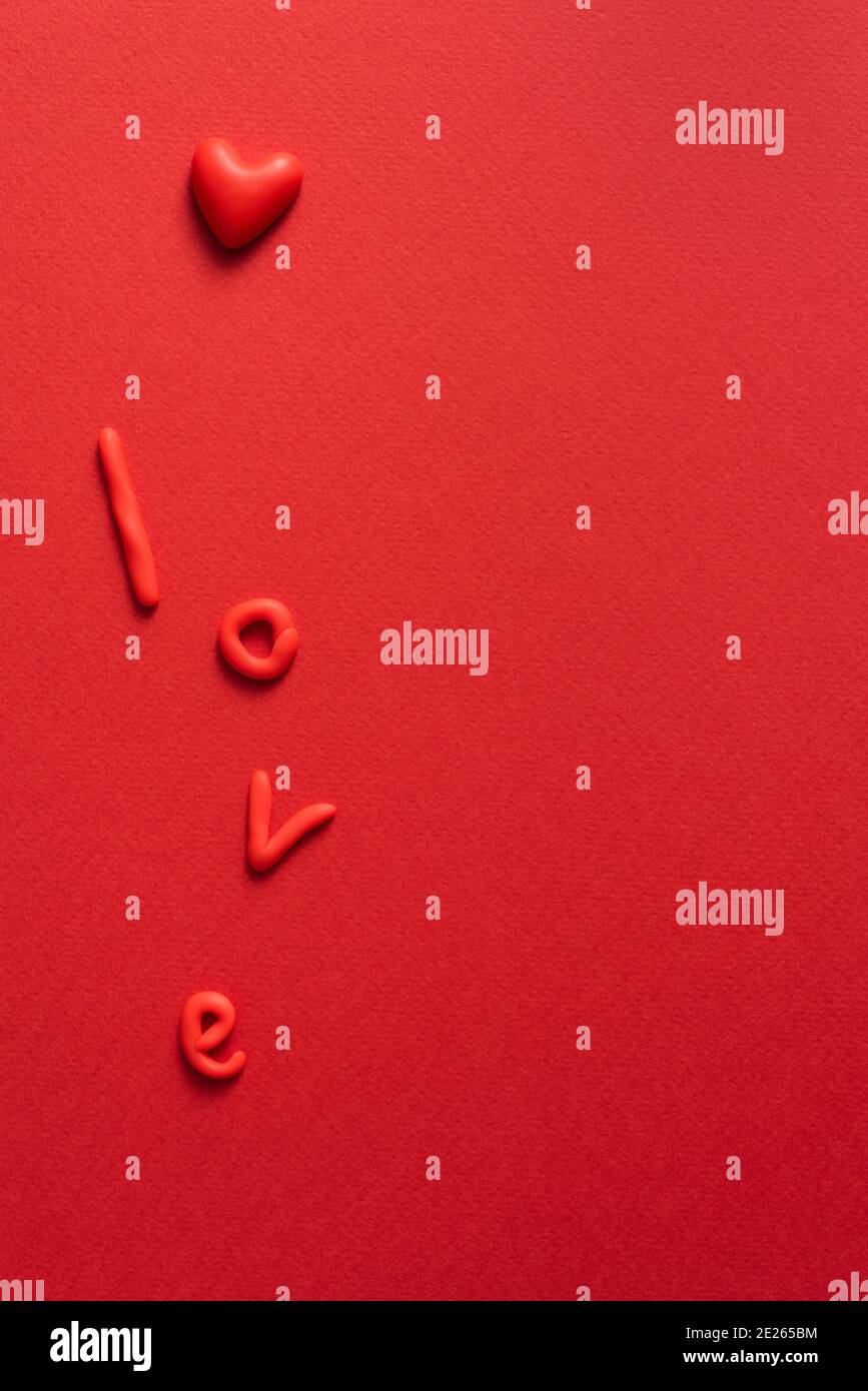 Fond minimaliste de Saint-Valentin de couleur rouge avec coeur et mot amour. Vue de dessus avec espace de copie Banque D'Images