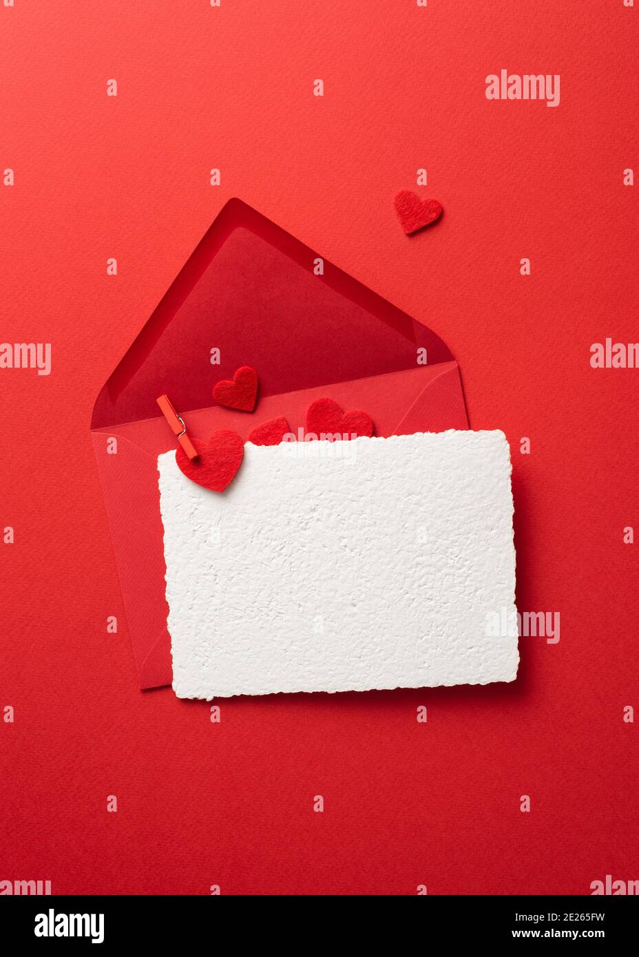 Vue du dessus carte de vœux de la Saint-Valentin maquette avec enveloppe sur fond rouge et coeurs. Plan de travail avec espace de copie Banque D'Images