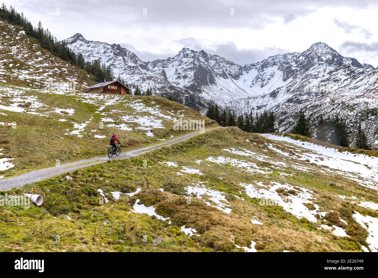 Deux motards de montagne qui surent en automne, dans la région de Montafon, dans le Vorarlberg, en Autriche, une cabine en bois sur une pente de montagne avec des taches de neige fondue Banque D'Images