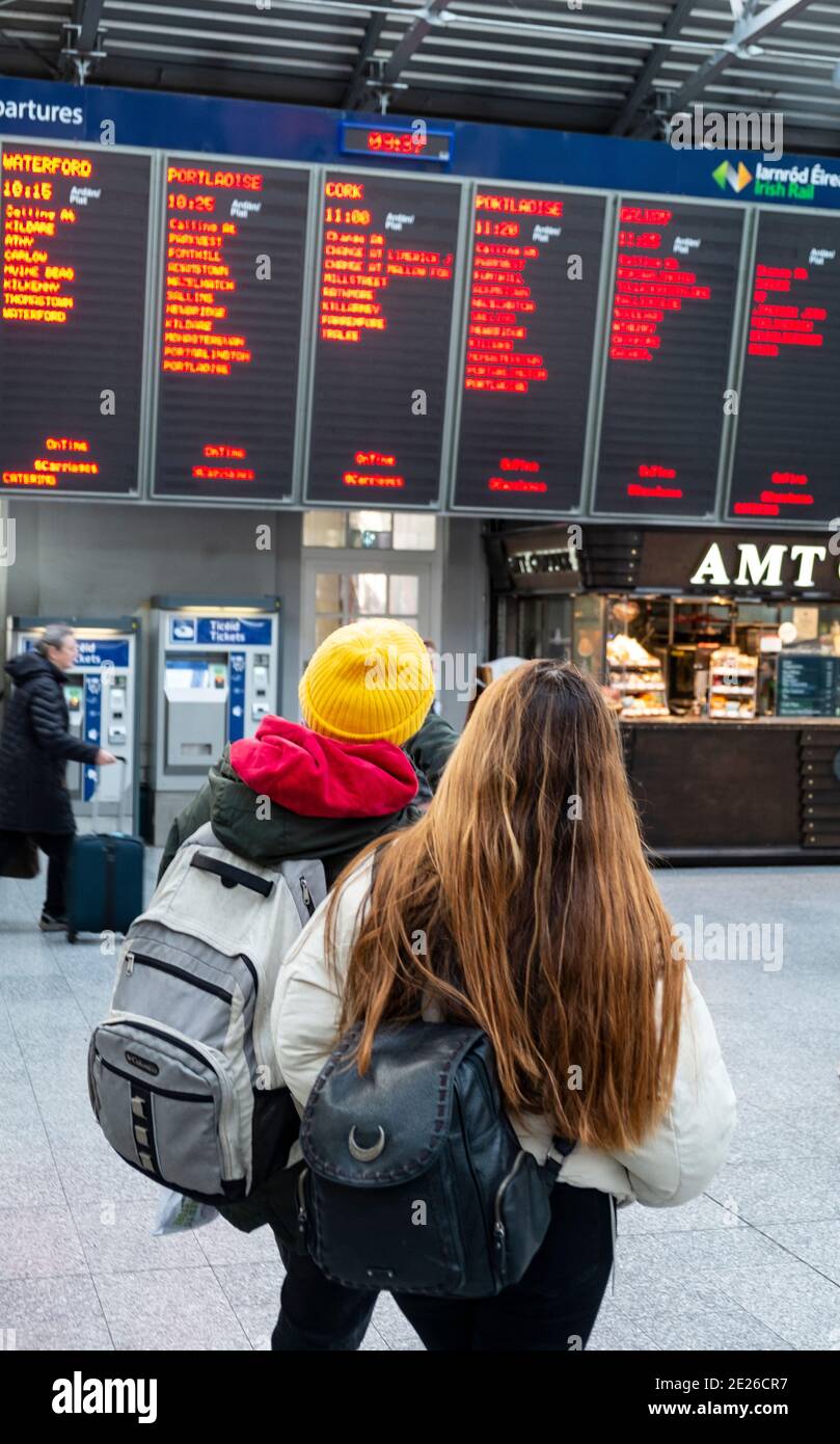 deux personnes regardent l'avis de départ à la gare Banque D'Images