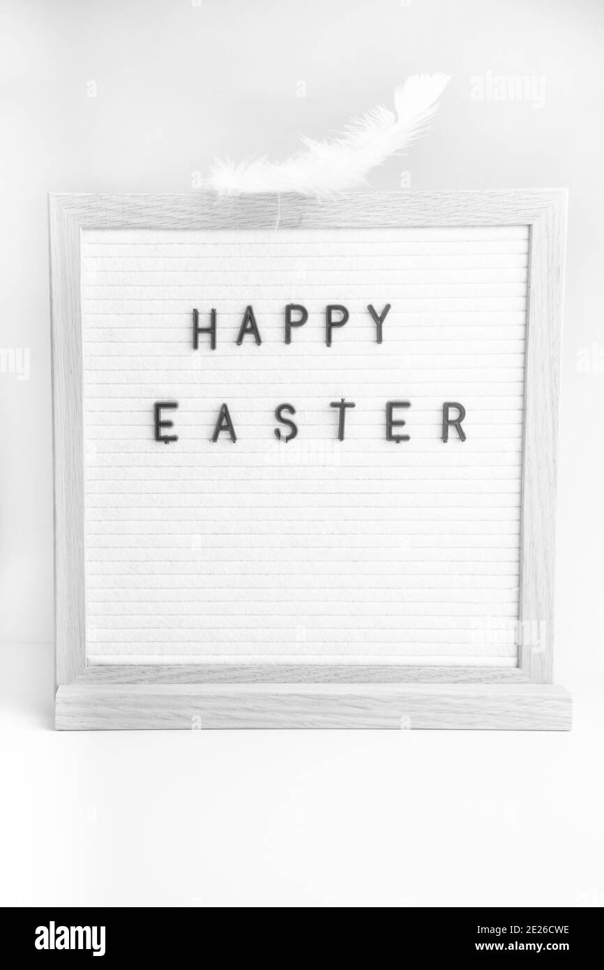 Easter salutations sur un letterboard avec texte Joyeux pâques, avec plume blanche Banque D'Images