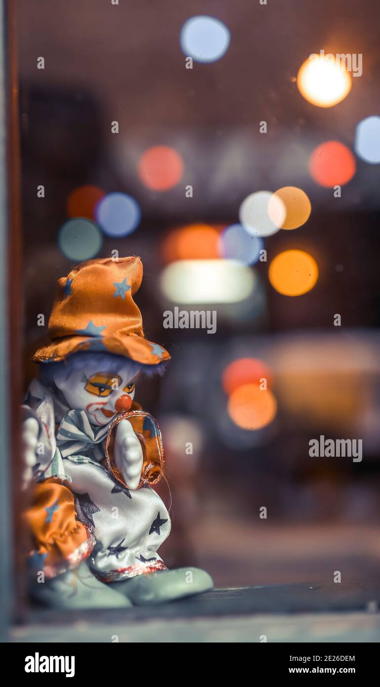mécontent clown jouet gros plan. arrière-plan bokeh. devant la fenêtre clown jouet triste dans la nuit Banque D'Images