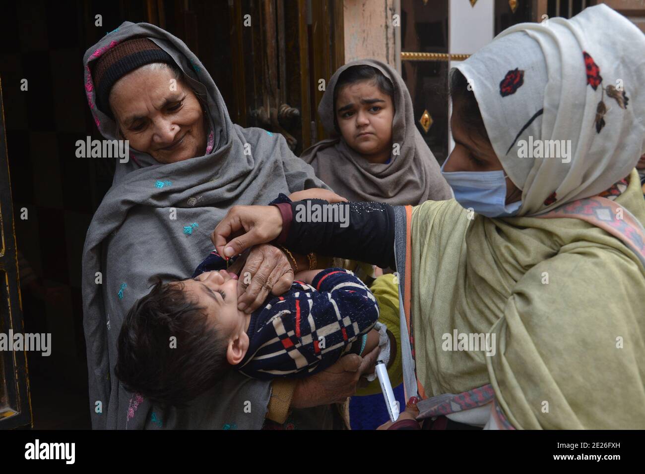 Lahore, Pakistan. 12 janvier 2021. Un travailleur de la santé pakistanais administre un vaccin contre la polio à un enfant lors d'une campagne de vaccination de porte à porte contre la polio à Lahore. Malgré une augmentation constante des cas de coronavirus, le Pakistan a lancé lundi une campagne de vaccination de cinq jours contre la polio dans des conditions de sécurité étroite, dans l'espoir d'éradiquer cette maladie invalidante pour les enfants cette année. (Photo de Rana Sajid Hussain/Pacific Press/Sipa USA) crédit: SIPA USA/Alay Live News Banque D'Images