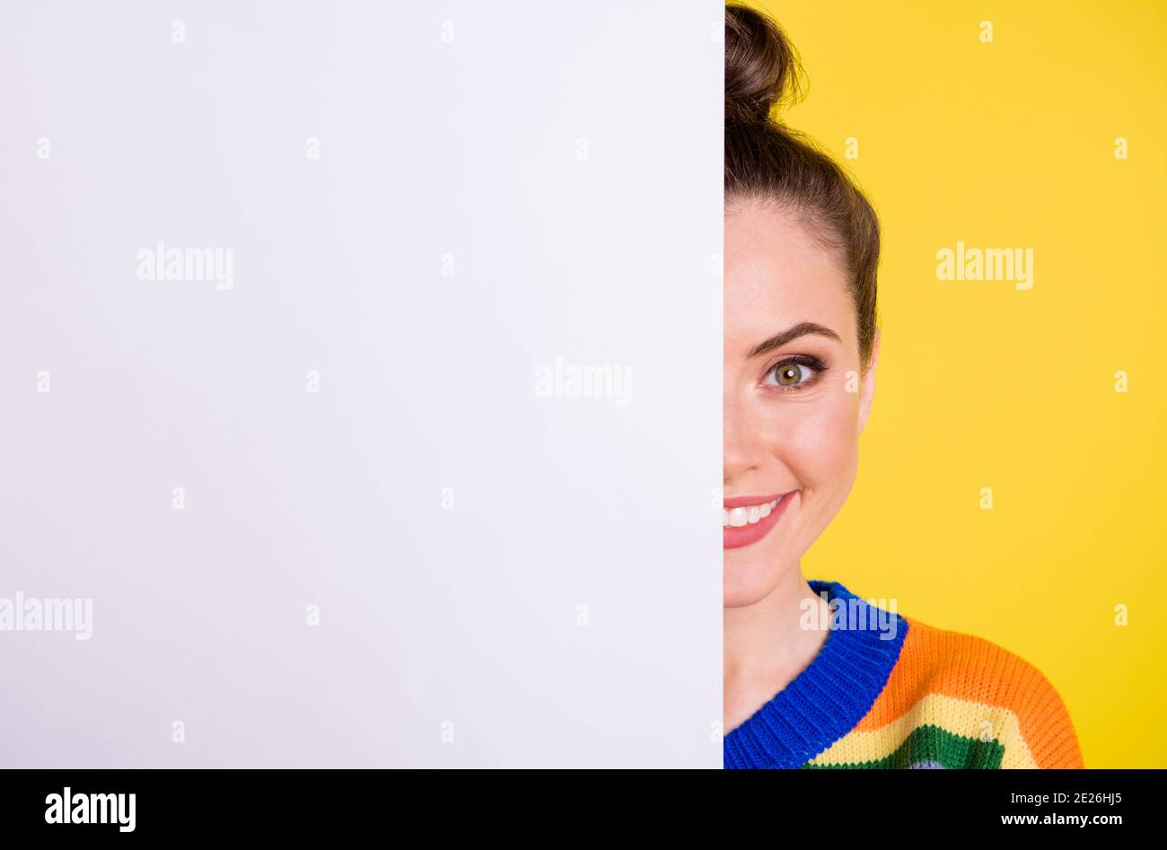 Photo de gai heureux brunette chignon cheveux fille couverture visage carte blanche promotion solde isolée sur fond jaune Banque D'Images