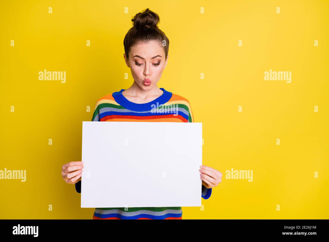 Photo de la mignonne brunette chignon femme cheveux tenir le papier publicitaire de panneau d'affichage espace regardez les nouvelles sur fond jaune vif Banque D'Images