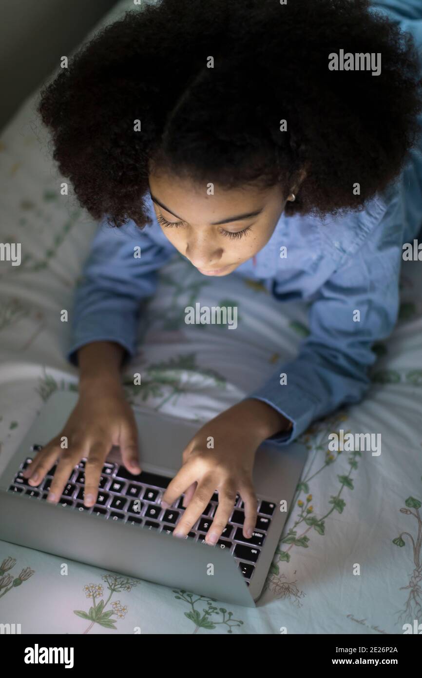 Vue de dessus d'une fille biraciale de dix ans travaillant sur un ordinateur portable Banque D'Images