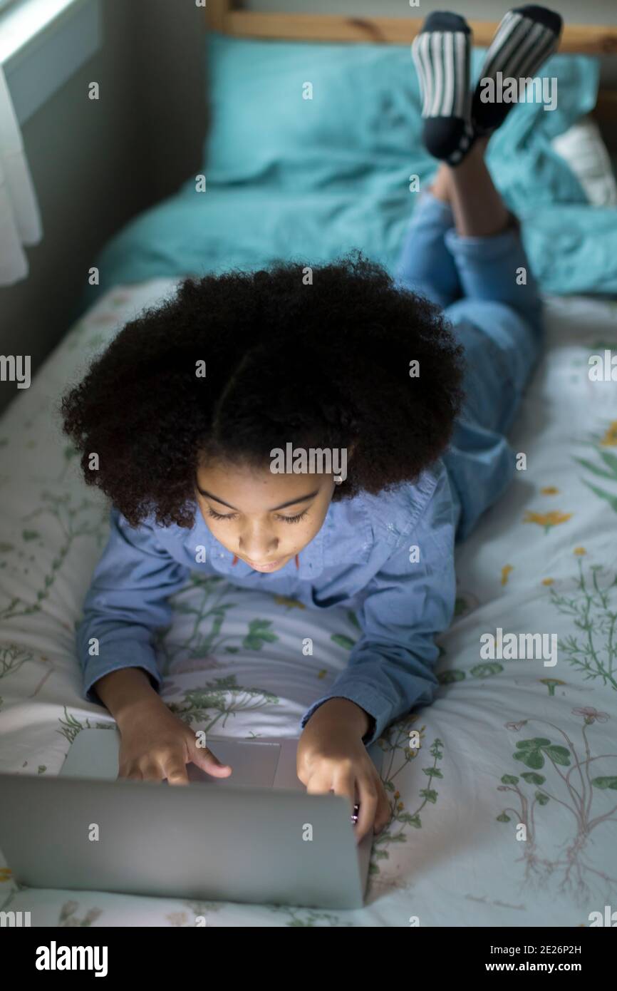 Vue en hauteur d'une jeune fille biraciale de dix ans qui travaille ordinateur portable Banque D'Images