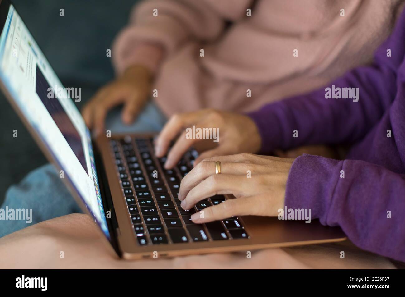 Gros plan des mains tapant sur un ordinateur portable avec les mains de l'enfant arrière-plan Banque D'Images