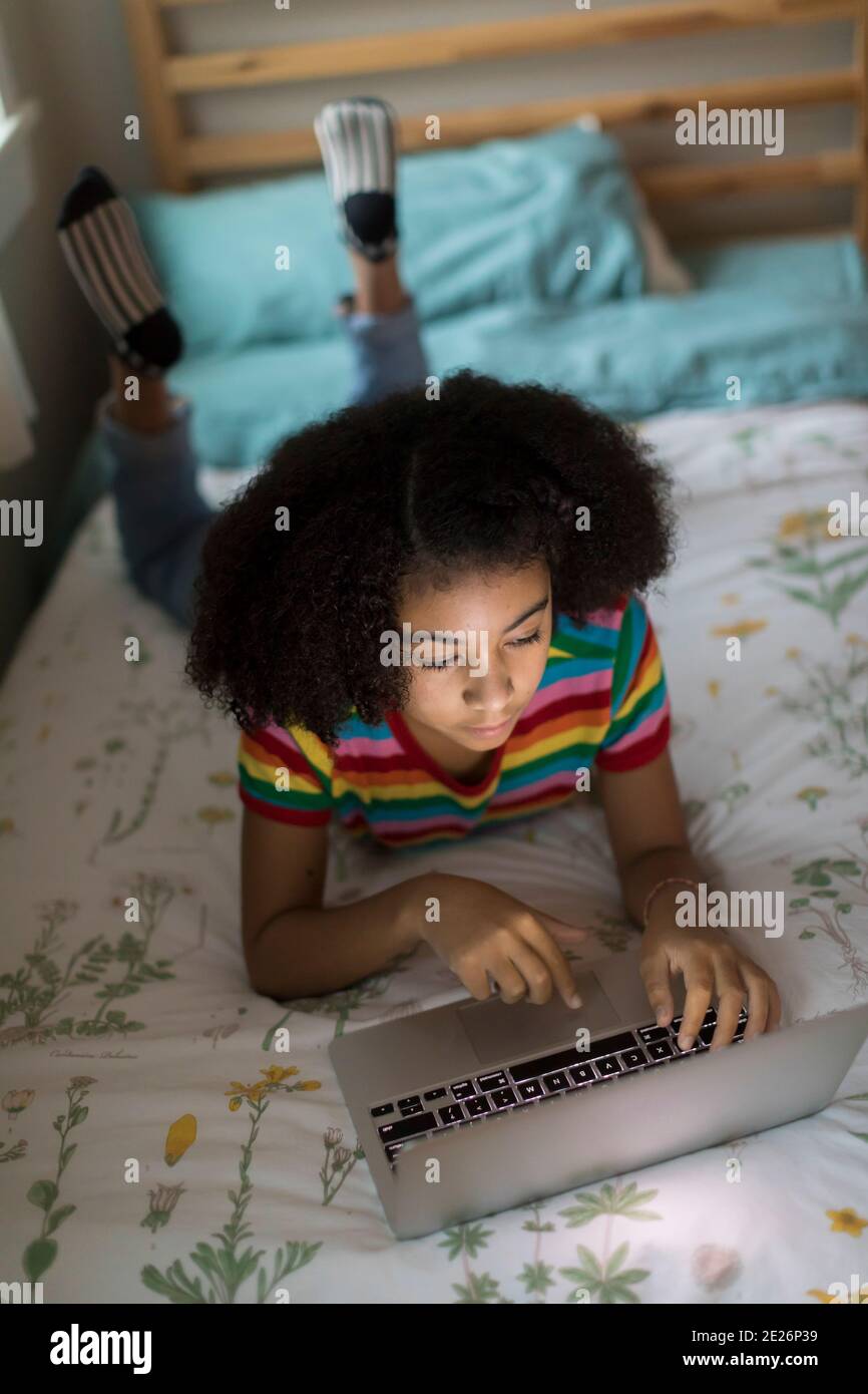 Vue en hauteur d'une jeune fille biraciale de dix ans qui travaille ordinateur portable Banque D'Images