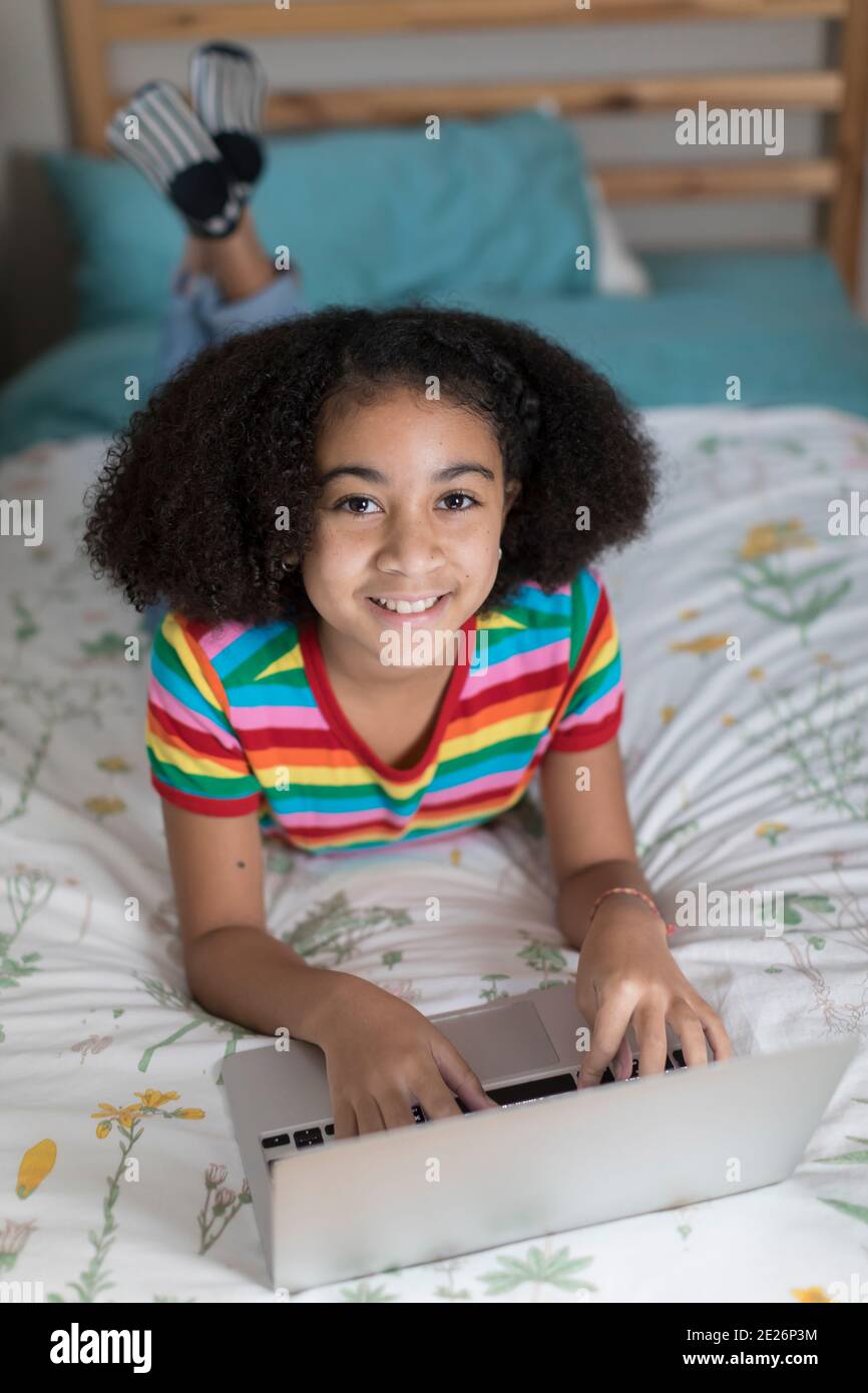 Fille biraciale de dix ans travaillant sur son ordinateur portable Apple et sourire Banque D'Images