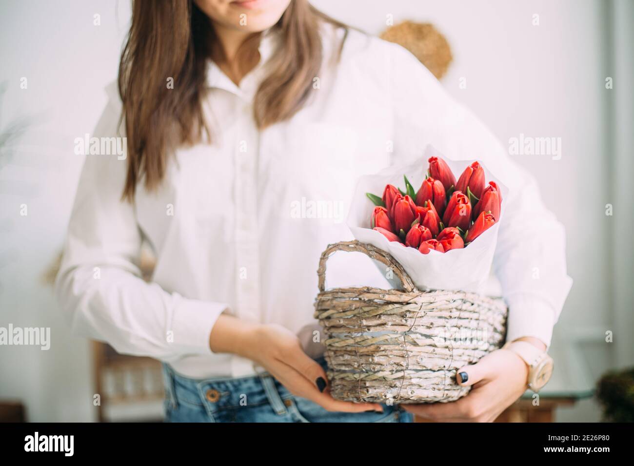 fleuriste femme tenant un panier avec des tulipes rouges dans le papier blanc. concept de livraison de magasin de fleurs Banque D'Images