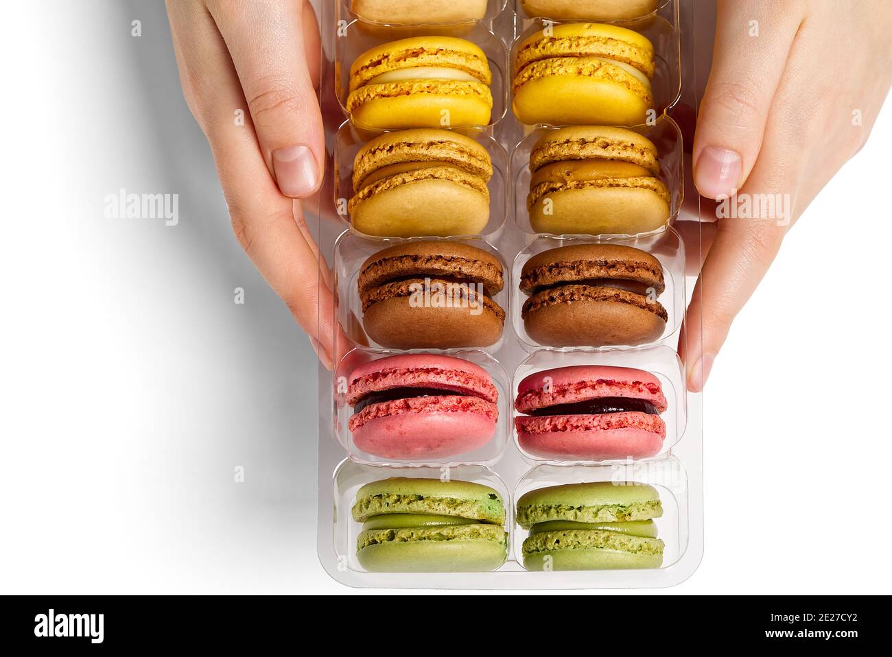 Macarons colorés en boîte dans les mains d'une femme sur fond blanc Banque D'Images