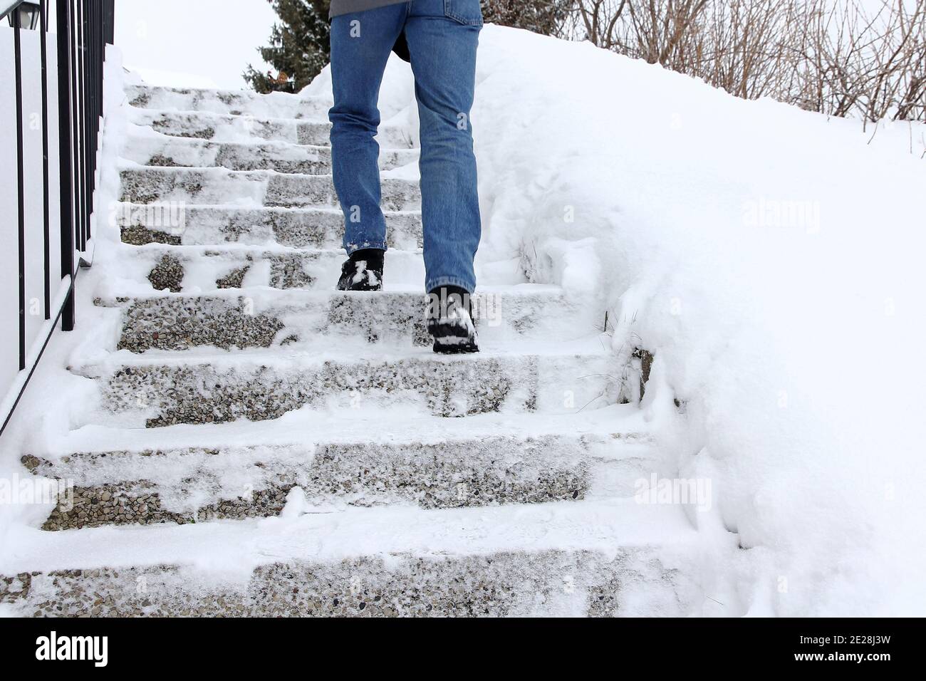 En hiver, il est dangereux de monter un escalier enneigé. Un homme marche dans un escalier en hiver Banque D'Images