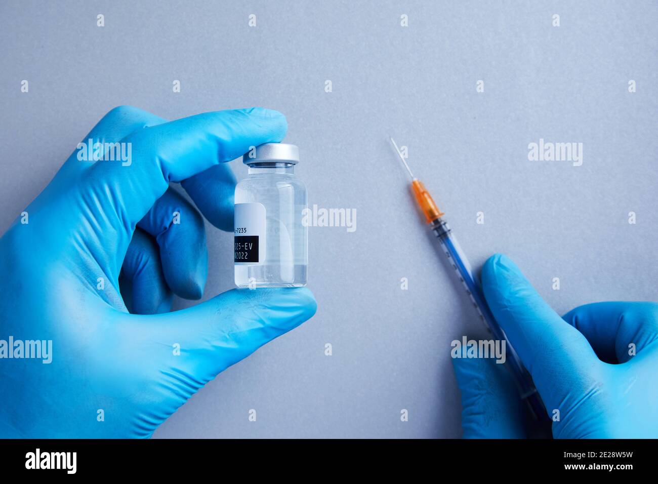 Les mains gantées tiennent un flacon de vaccin transparent pour la science Banque D'Images