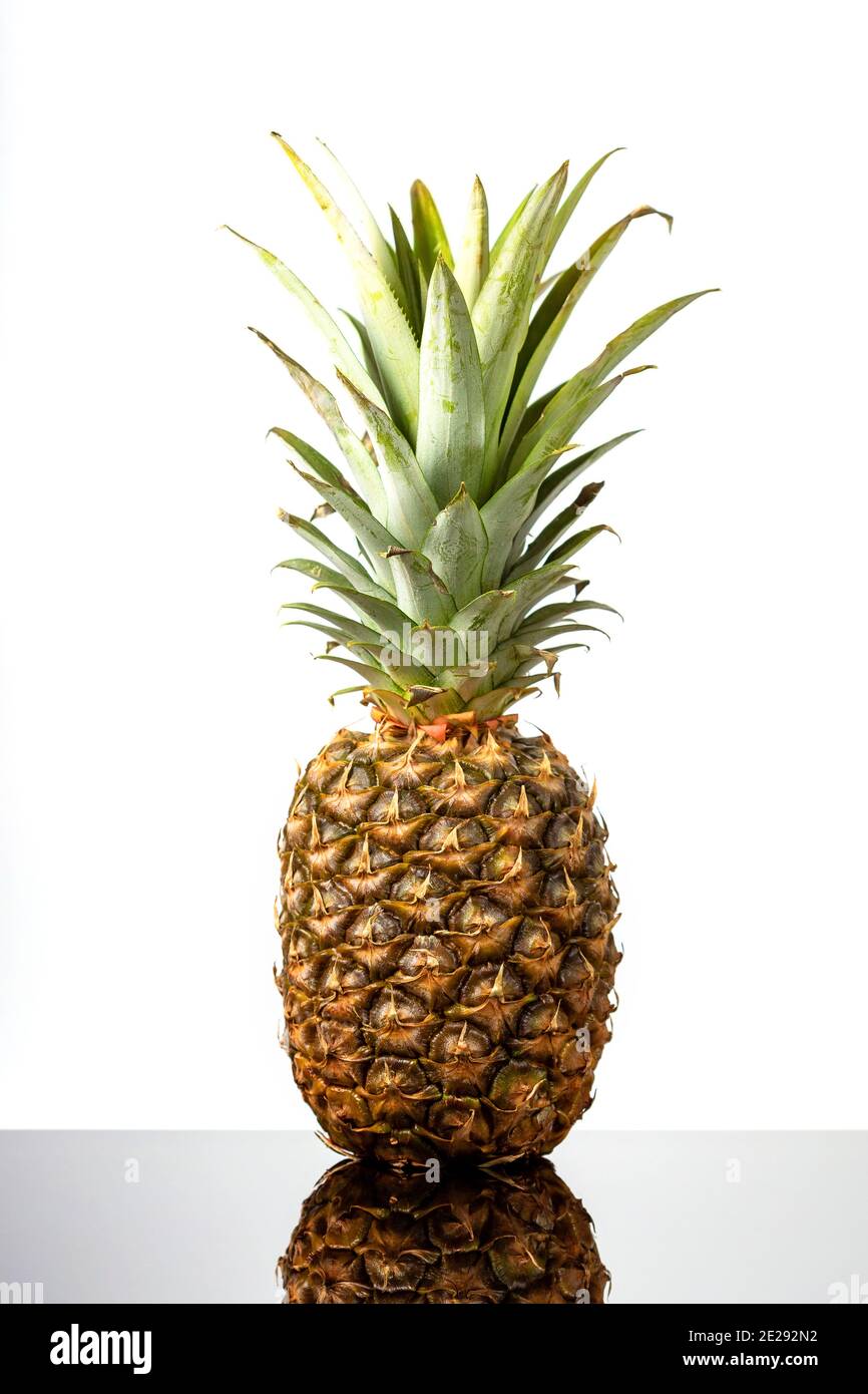 Ananas mûr et frais sur table en verre noir sur fond blanc Banque D'Images