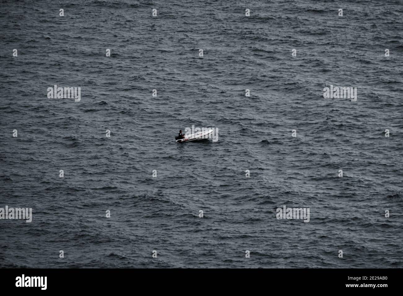 Homme flottant par le bateau gonflable dans le vague ouvert mer Banque D'Images