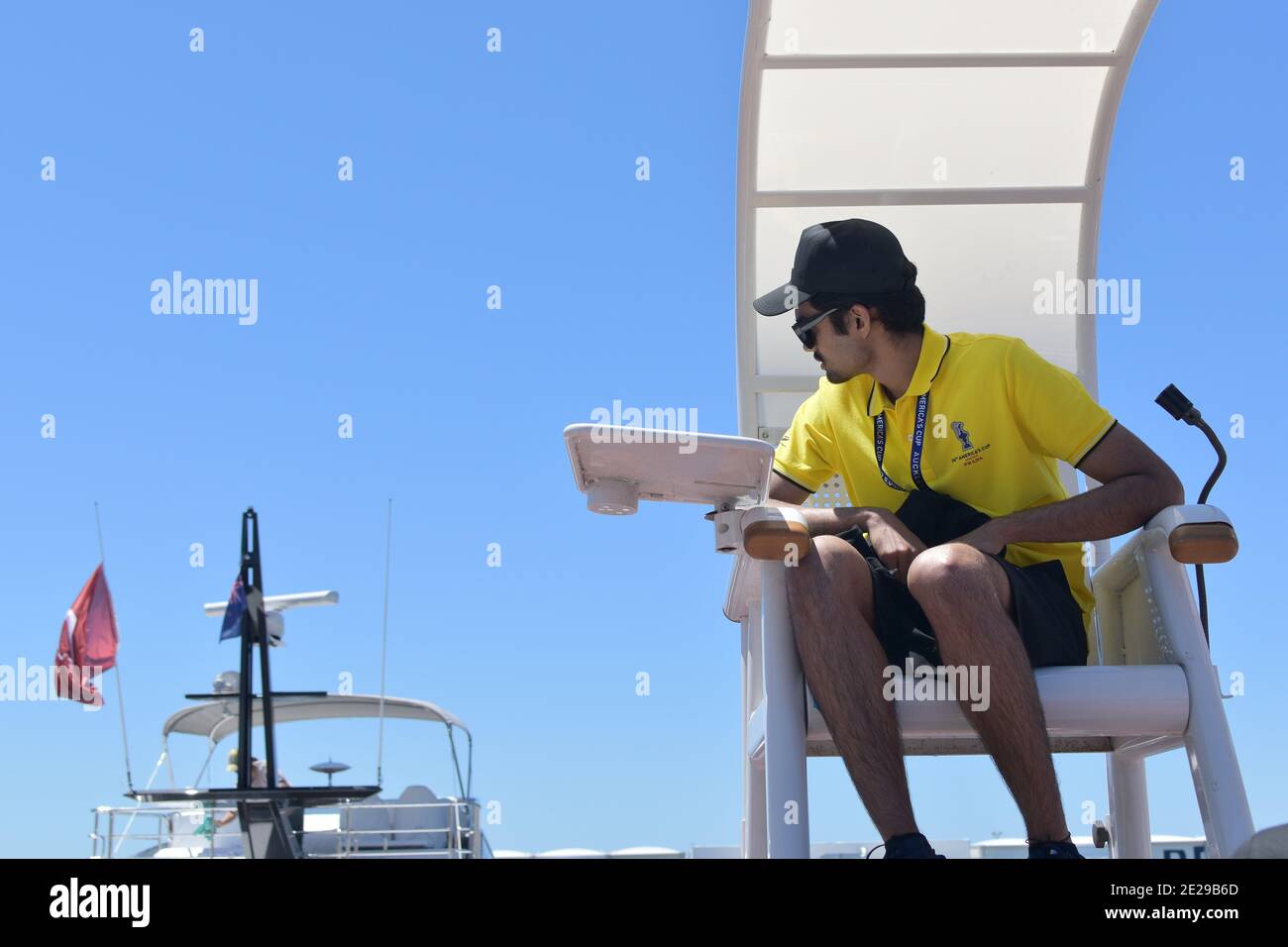 AUCKLAND, NOUVELLE-ZÉLANDE - 03 janvier 2021 : vue du volontaire de la coupe de l'Amérique en jersey jaune assis sur une chaise d'arbitre avec parapluie Banque D'Images