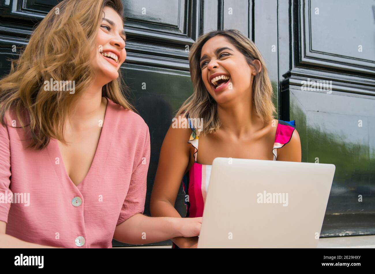 Deux amis utilisant un ordinateur portable à l'extérieur. Banque D'Images