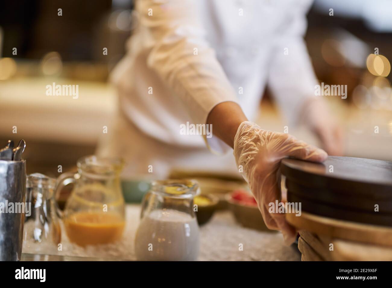 Photo rognée du chef en utilisant des gants jetables tout en déplaçant la cuisine autour de l'équipement Banque D'Images