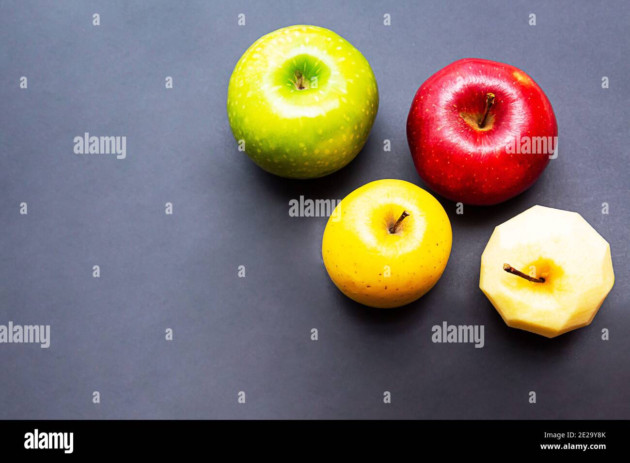 Pommes vertes, jaunes, rouges et pommes sans pelage sur fond noir. Concept de nourriture saine avec espace de copie Banque D'Images