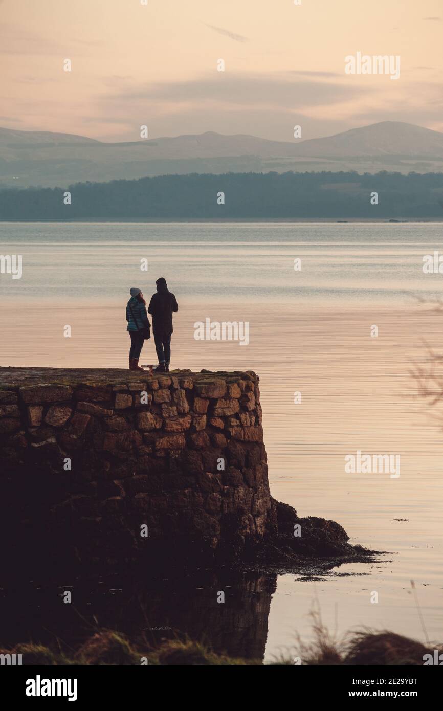 Un couple debout sur le vieux port près du club de voile de Dalgety Bay, Fife, Écosse. Banque D'Images