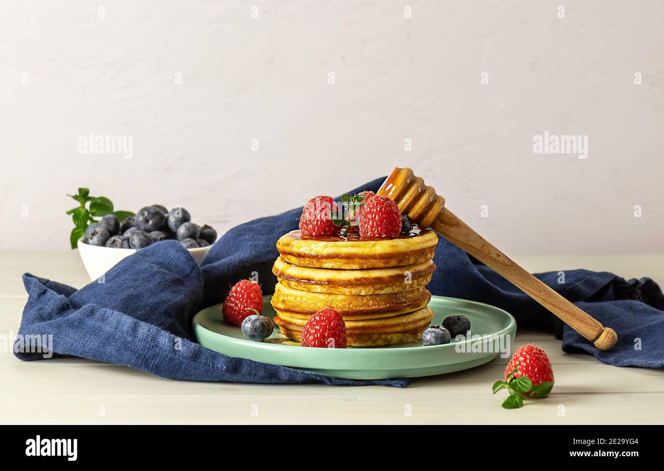 Crêpes américaines savoureuses aux framboises, aux bleuets et au miel. Concept petit déjeuner avec espace copie. Banque D'Images