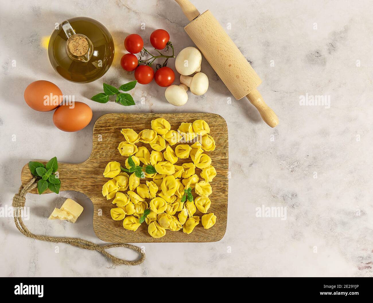 Tortellini de pâtes italiennes crues maison aux champignons, au basilic et à la tomate. Vue de dessus, espace de copie. Banque D'Images
