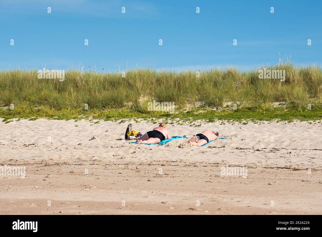 Personnes (matures, méconnaissables, avec vue sur l'arrière) se détendant et se baignant au soleil sur la plage de sable en Normandie, en France. Écotourisme. Vacances d'été. Banque D'Images