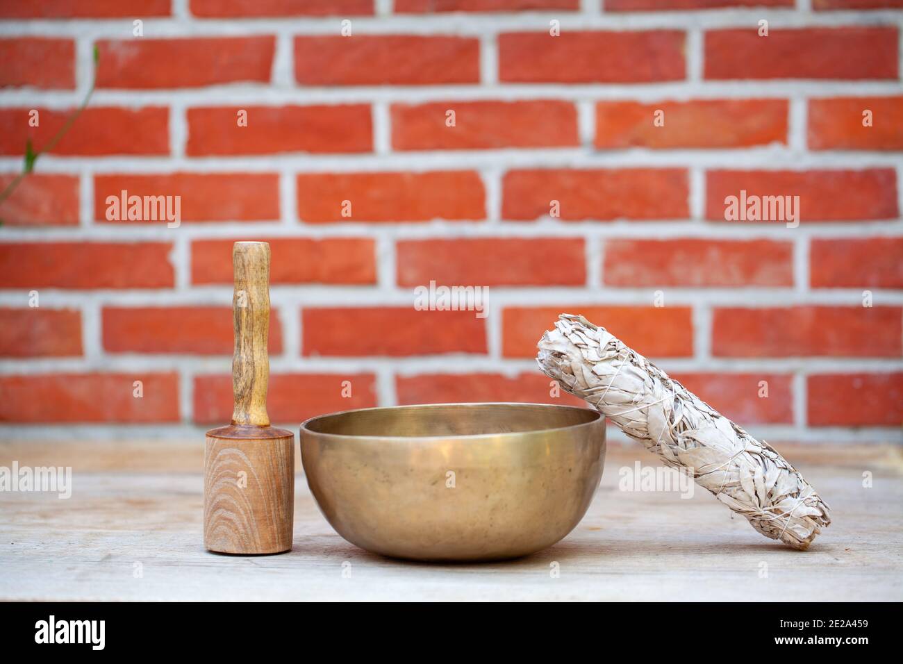 Bols de chant tibétains avec bâtons et bâton de sauge sur le fond de mur - instruments de musique pour la méditation, la relaxation après la pratique de yoga et le massage curatif. Photo de haute qualité Banque D'Images