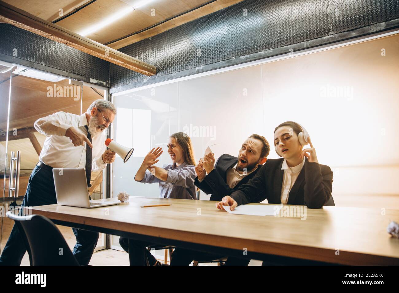 Rapport. Un patron en colère avec un mégaphone hurlant aux employés au bureau, des collègues effrayés et agacés à l'écoute de la table ont été stressés. Concept de réunion, d'affaires, de bureau amusant. Hurler fou. Banque D'Images