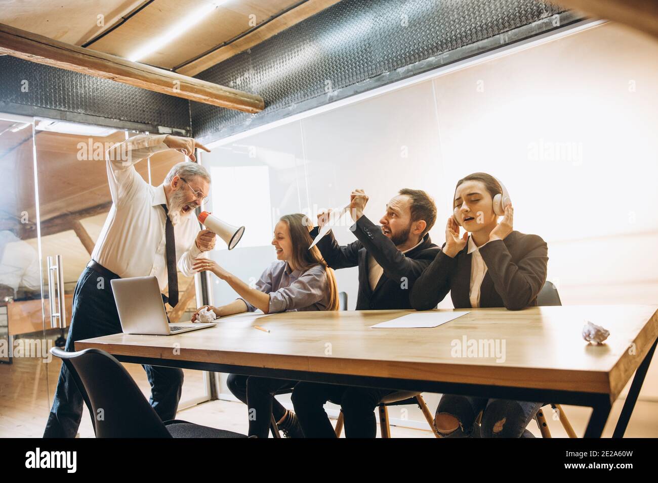 Restez calme. Un patron en colère avec un mégaphone hurlant aux employés au bureau, des collègues effrayés et agacés à l'écoute de la table ont été stressés. Concept de réunion, d'affaires, de bureau amusant. Hurler fou. Banque D'Images