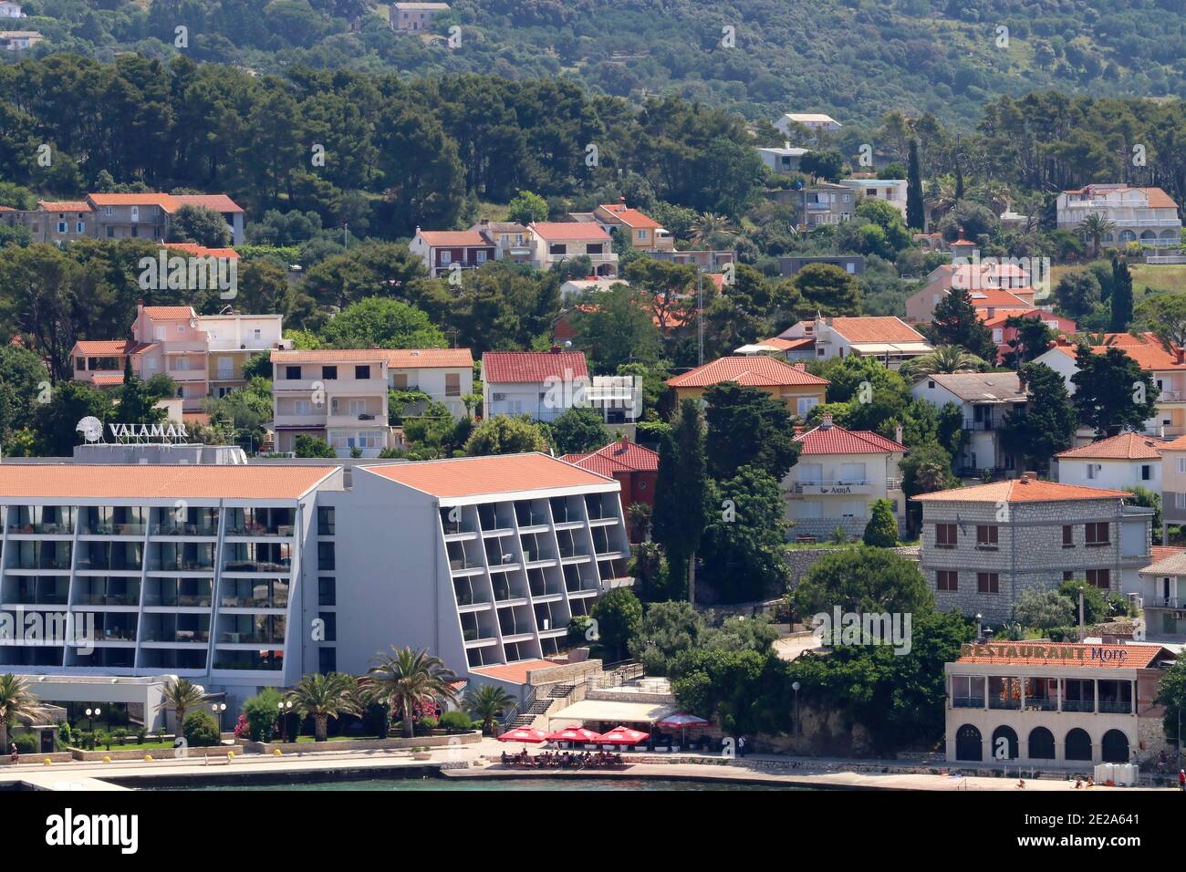 Croatie, région de Kvarner, Rab Island Hôtel moderne sur le front de mer avec des collines derrière elle. Banque D'Images