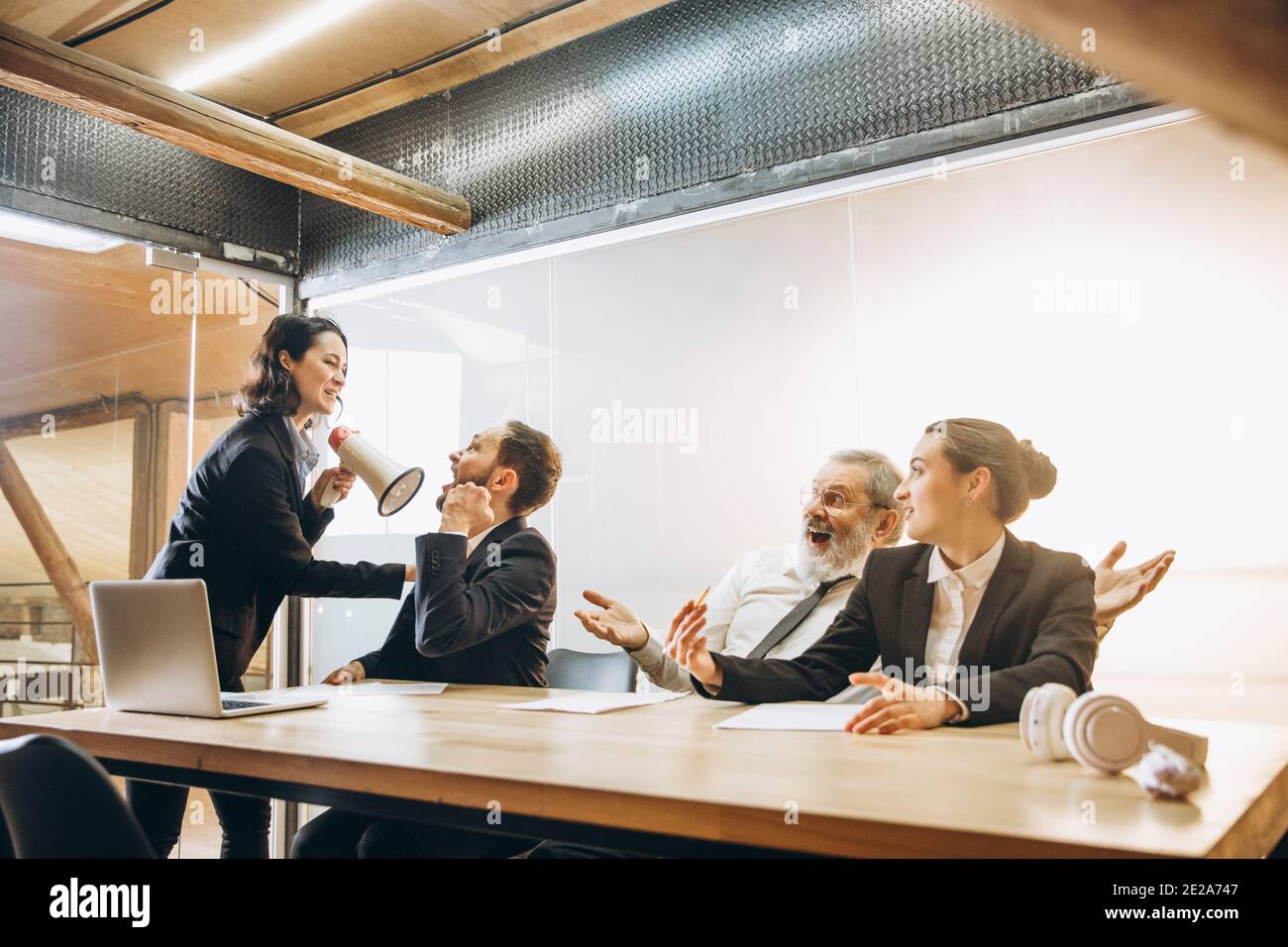 Dame patron. Une femme en colère avec le mégaphone hurlait aux employés au bureau, effrayée et agacée des collègues à l'écoute de la table stressée. Concept de réunion, d'affaires, de bureau amusant. Hurler fou. Banque D'Images