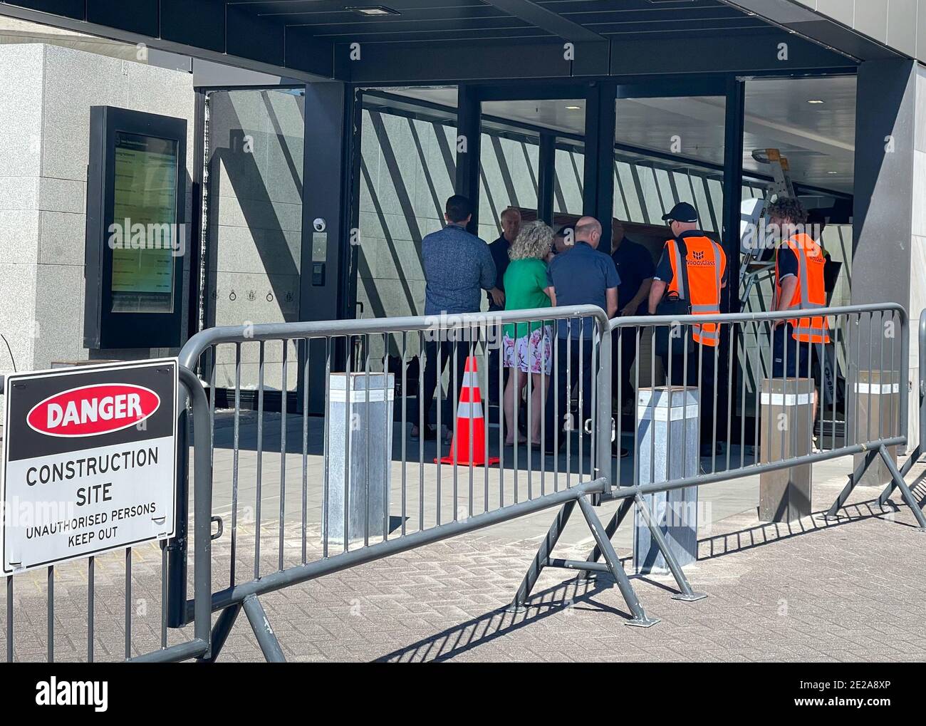 Wellington, Nouvelle-Zélande. 13 janvier 2021. Le personnel de sécurité et le personnel de travail se réunissent à l'entrée principale brisée du Parlement de la Nouvelle-Zélande à Beehive, Wellington, Nouvelle-Zélande, le 13 janvier 2021. La police néo-zélandaise a arrêté un homme de 31 ans après avoir lancé une attaque à la hache contre le Parlement mercredi matin. La motivation de l'attaque n'est pas claire, et l'homme a été accusé de dommages intentionnels et de possession d'une arme offensive, ont rapporté les médias locaux. Crédit: Meng Tao/Xinhua/Alamy Live News Banque D'Images