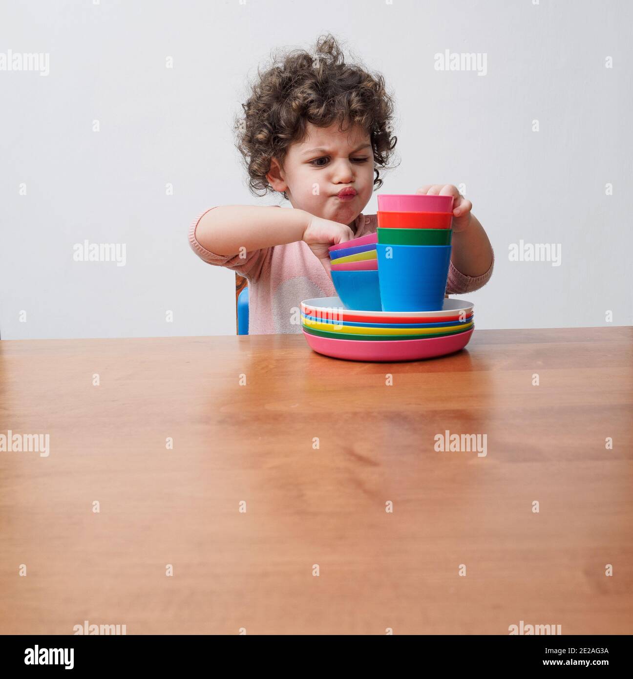 Un tout-petit joue avec des plats en plastique à une table Banque D'Images