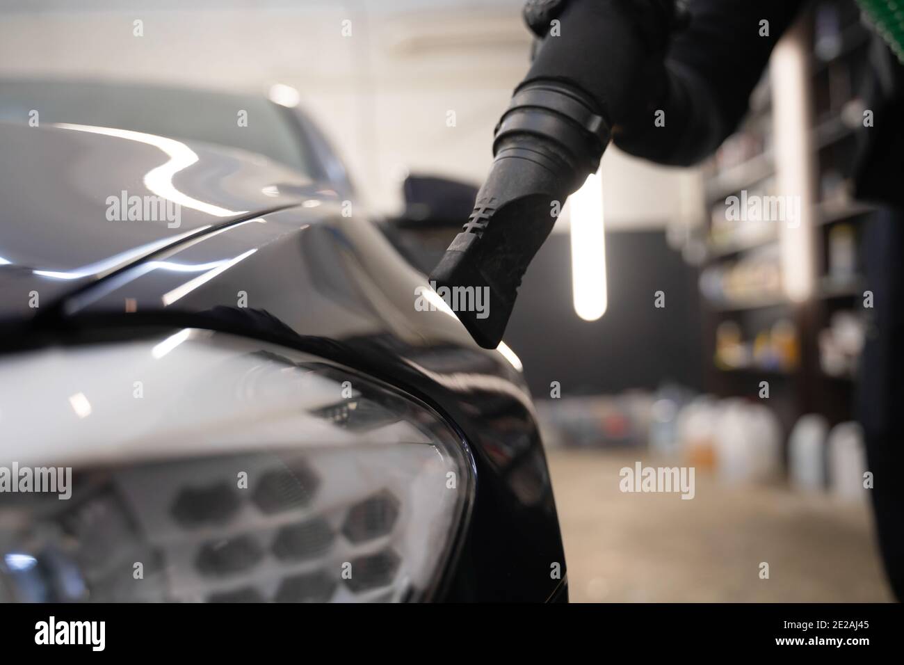 Processus de séchage de voiture après lavage. L'homme équipé d'un aspirateur élimine les gouttelettes d'eau de la voiture. Concept de lavage automatique professionnel Banque D'Images
